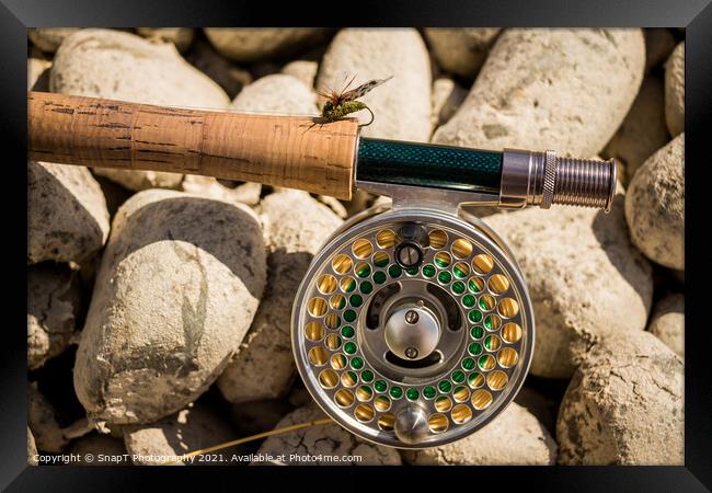 A close up of a trout fly rod, reel and line on rocks, with a cicada fly Framed Print by SnapT Photography