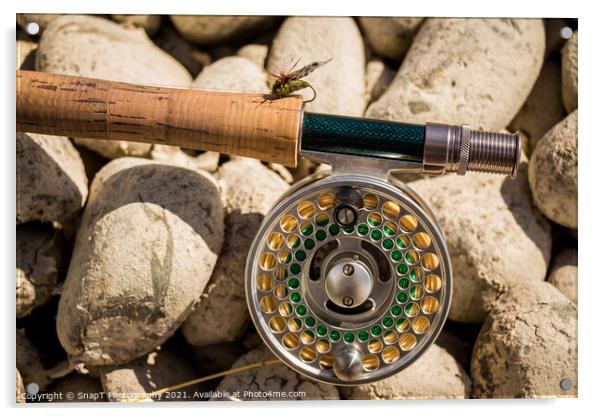 A close up of a trout fly rod, reel and line on rocks, with a cicada fly Acrylic by SnapT Photography