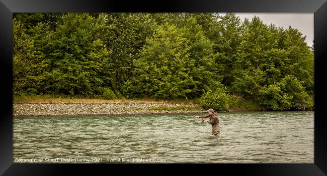 A fly fisherman spey casting while wading in a fast flowing, green, glacial river. Framed Print by SnapT Photography