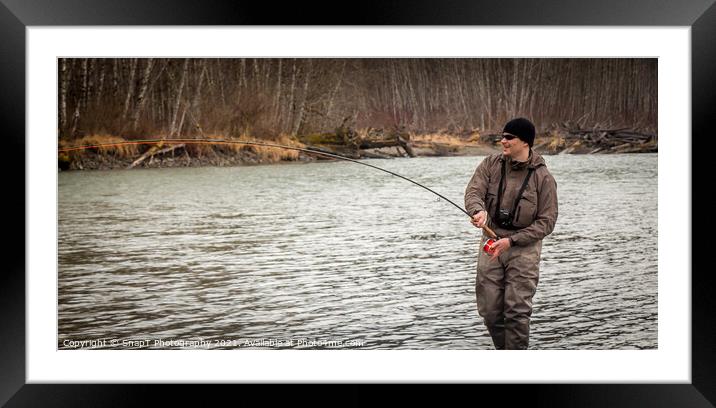 A fly fisherman hooked into a big fish in a river with the rod bent Framed Mounted Print by SnapT Photography