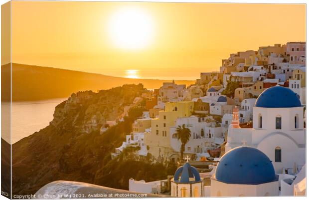 Blue domed churches and traditional white houses facing Aegean Sea with warm sunset light in Oia, Santorini, Greece Canvas Print by Chun Ju Wu