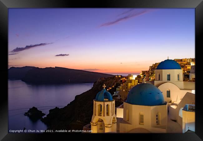 Blue domed churches and traditional white houses facing Aegean Sea with warm sunset light in Oia, Santorini, Greece Framed Print by Chun Ju Wu