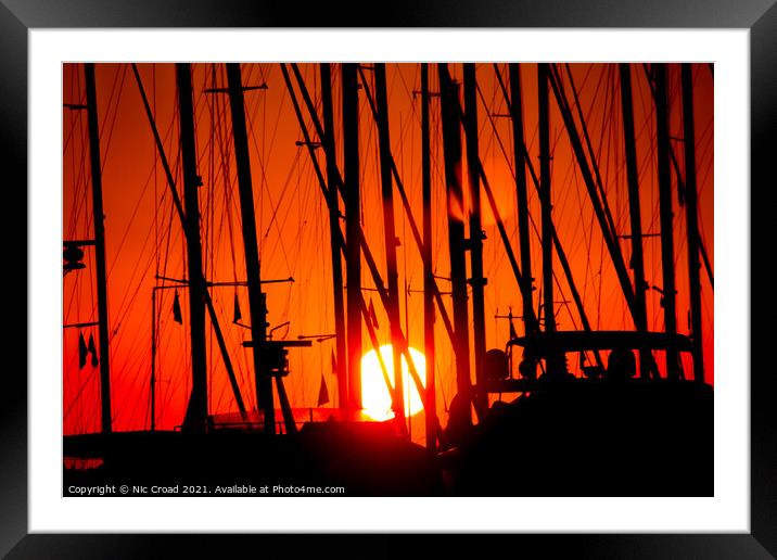Sunset through silhouetted yacht masts Framed Mounted Print by Nic Croad