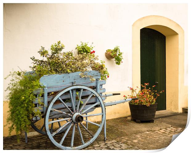 Old fashioned cart for horse with flowers by old white wall Print by Steve Heap