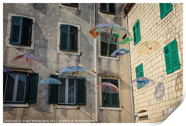 Flying umbrellas in a square in the old town of Kotor, in Montenegro Print by SnapT Photography