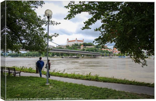 People walking along a footpath by the River Danube with the Bratislava Castle Canvas Print by SnapT Photography