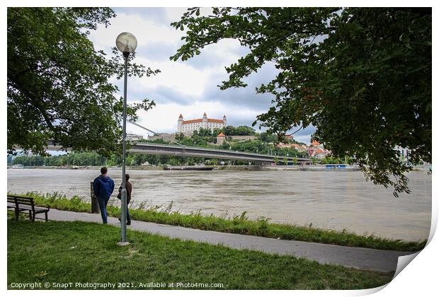 People walking along a footpath by the River Danube with the Bratislava Castle Print by SnapT Photography