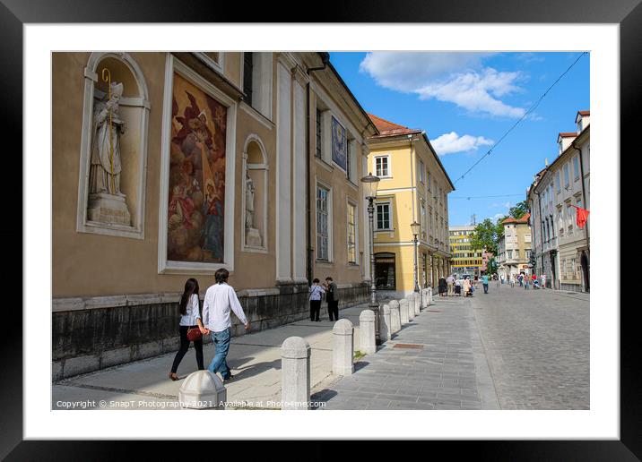 Tourists walking past the art on the wall at Ljubljana Cathedral, Slovenia Framed Mounted Print by SnapT Photography