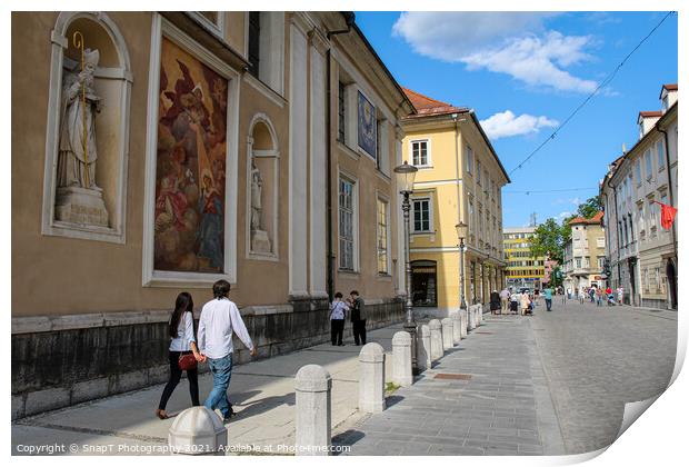 Tourists walking past the art on the wall at Ljubljana Cathedral, Slovenia Print by SnapT Photography