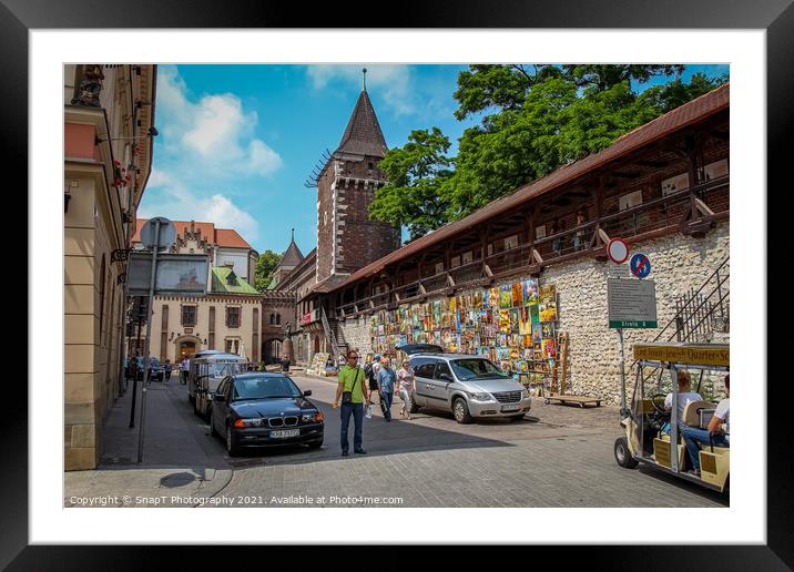Artists pictures displayed on the wall of St. Florian's Gate on Pijarska Street, old town of Krakow, Poland Framed Mounted Print by SnapT Photography