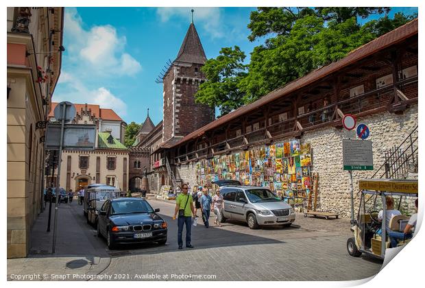 Artists pictures displayed on the wall of St. Florian's Gate on Pijarska Street, old town of Krakow, Poland Print by SnapT Photography