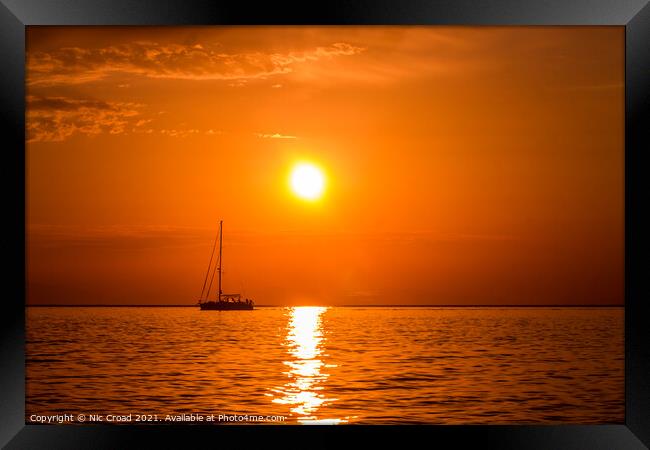 Yacht on the sea at sunset Framed Print by Nic Croad