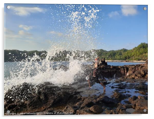 A big wave hits a man on a rock plateau Acrylic by Hanif Setiawan