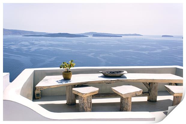 Santorini, Greece: A pot with flower or plant and a plate on a wooden table with wooden chair against beautiful sea ocean background with mountains Print by Arpan Bhatia