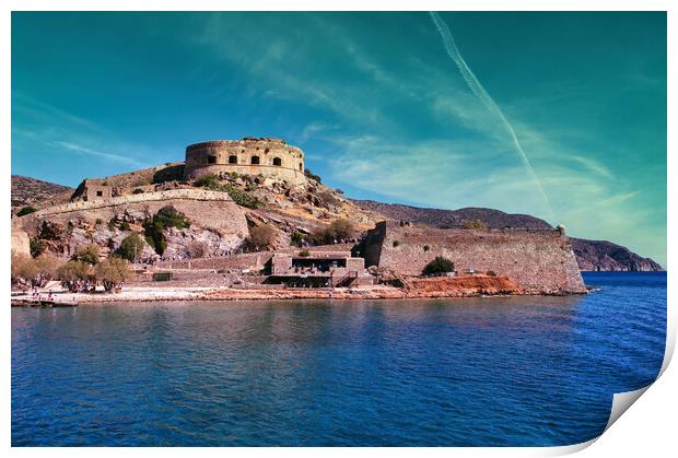 Crete, Greece: Wide angle view of Spinalonga unhabited island with a 16th century venetian fortress and the ruins of a formar leper colony against cloudy blue sky and blue water in the foreground Print by Arpan Bhatia