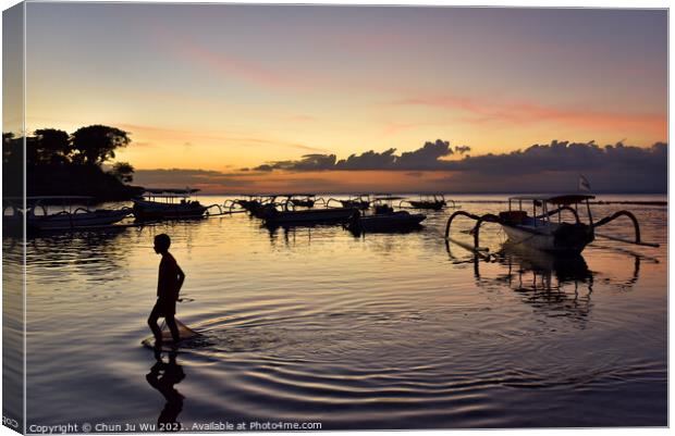 A boy walking through the sea water with sunset at background in Bali, Indonesia Canvas Print by Chun Ju Wu