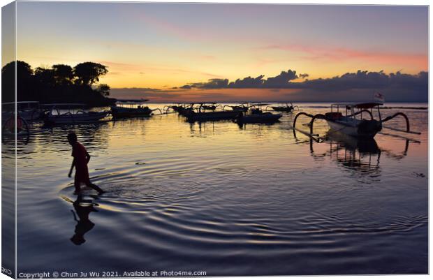 A boy walking through the sea water with sunset at background in Bali, Indonesia Canvas Print by Chun Ju Wu