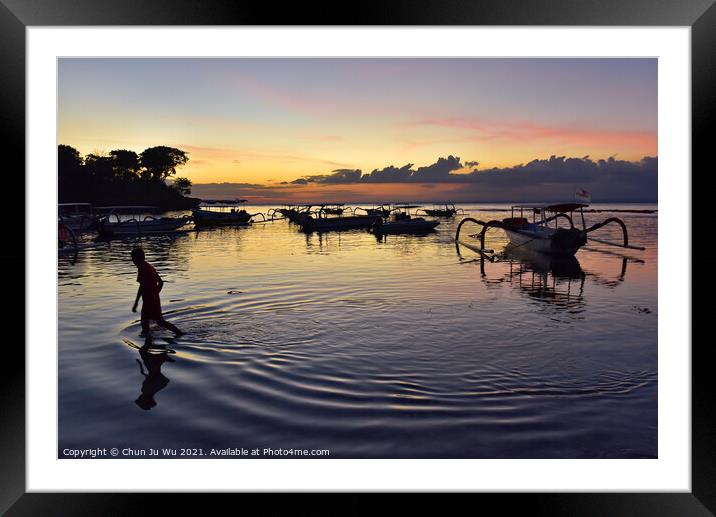 A boy walking through the sea water with sunset at background in Bali, Indonesia Framed Mounted Print by Chun Ju Wu