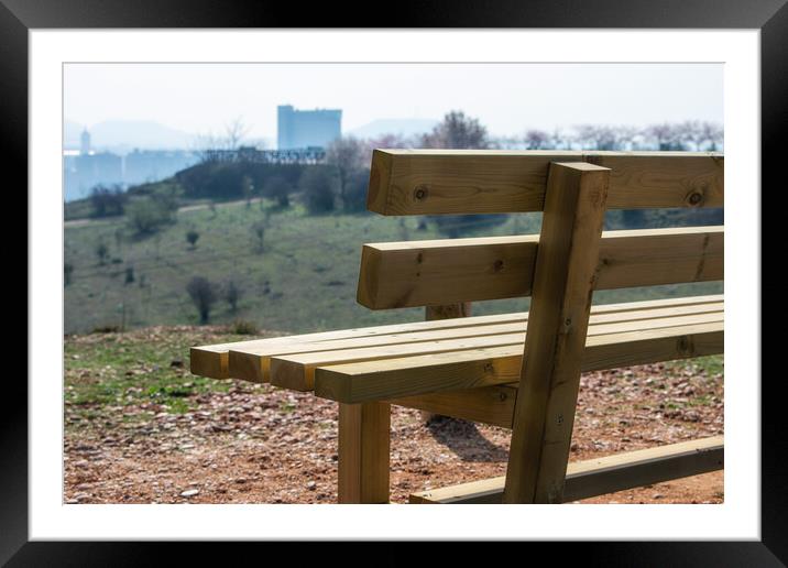 close empty wooden bench in spring park over the city Framed Mounted Print by David Galindo