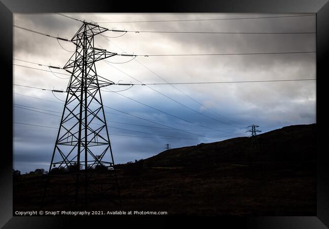 Electricity pylons in a field on a cloudy day in w Framed Print by SnapT Photography