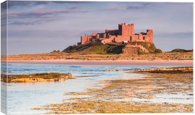 Bamburgh Castle, Northumbria at sunset Canvas Print by Alan Dunnett
