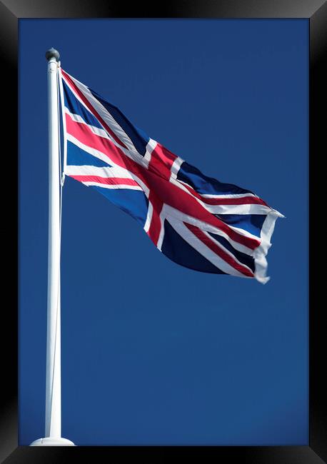 Union Jack flying against blue sky Framed Print by Neil Overy