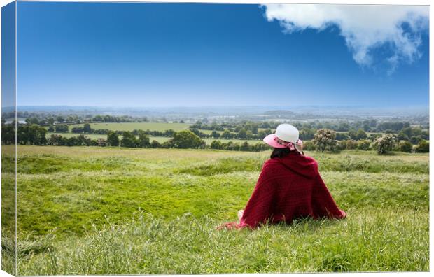 Woman sitting down in grassy farm fields while looking at the ho Canvas Print by Thomas Baker