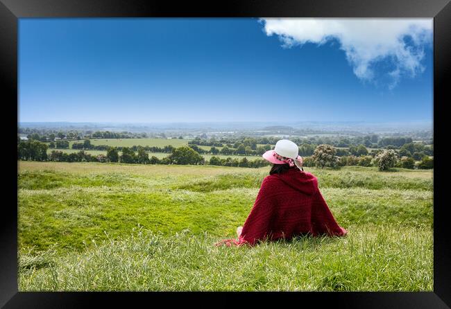 Woman sitting down in grassy farm fields while looking at the ho Framed Print by Thomas Baker