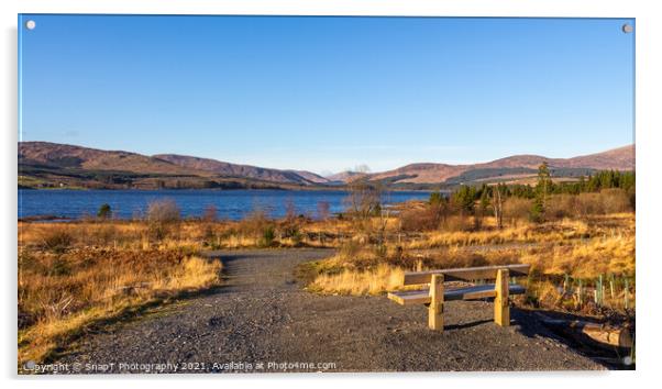 A wooden bench overlooking Clatteringshaws Loch on a sunny winters day Acrylic by SnapT Photography