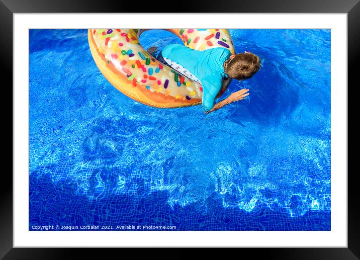 6-year-old boy bathing in a transparent pool playing with a larg Framed Mounted Print by Joaquin Corbalan