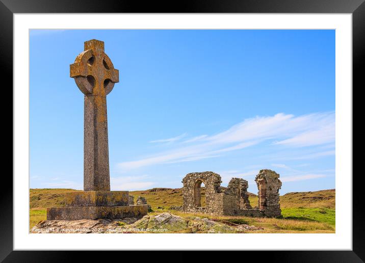Celtic cross and the remains of St. Dwynwen church Framed Mounted Print by Kevin Hellon
