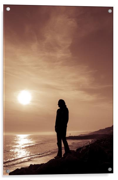 Silhouetted girl stands by sea at sunset Acrylic by George Cairns