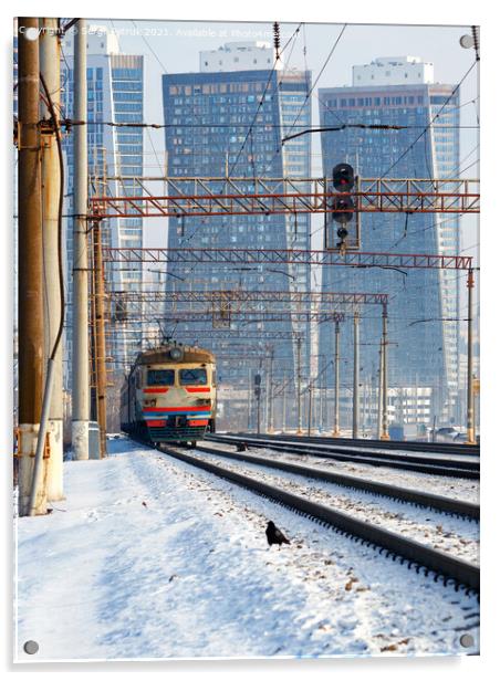 An electric train moves on rails against the backdrop of a cityscape of skyscrapers in a winter haze. Acrylic by Sergii Petruk