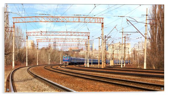 Passenger train cars of the train ride on the railway tracks in the background of the cityscape Acrylic by Sergii Petruk