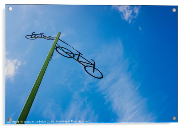 Post with the figure of some bicycles indicating the road, with blue sky and clouds in the background. Acrylic by Joaquin Corbalan