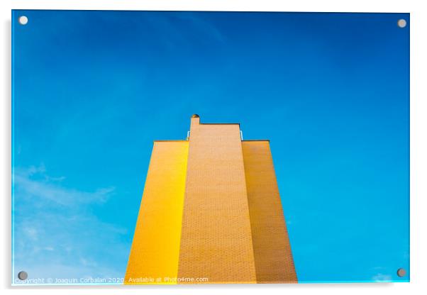 High brick building, warm and yellow at sunset, with the background of an intense blue sky and copy space, minimalist architecture. Acrylic by Joaquin Corbalan