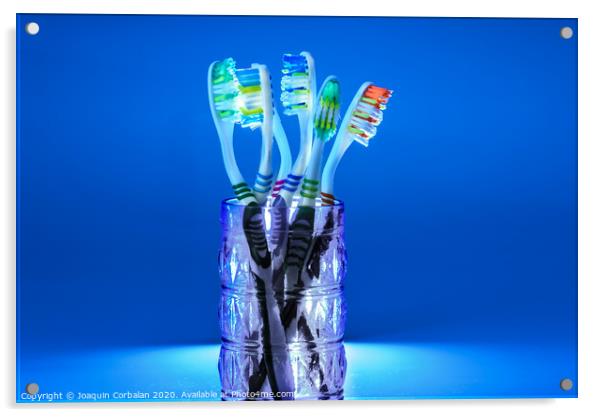 Many new plastic toothbrushes inside a glass, isolated on striking blue background, with copy space. Acrylic by Joaquin Corbalan