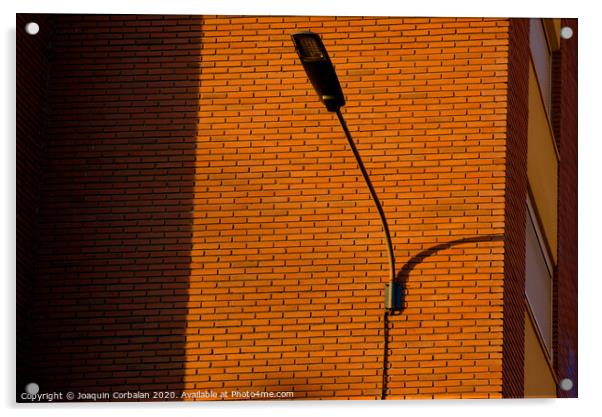 A deep red brick wall supports a lamppost, contrasting and bright colors. Acrylic by Joaquin Corbalan