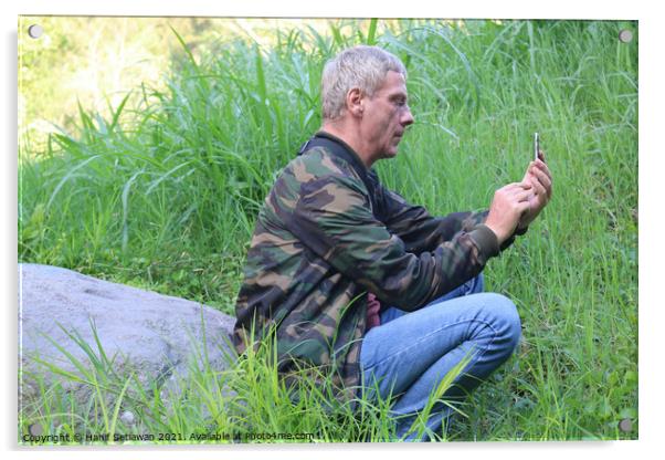 A Caucasian senior man using his phone in a meadow Acrylic by Hanif Setiawan