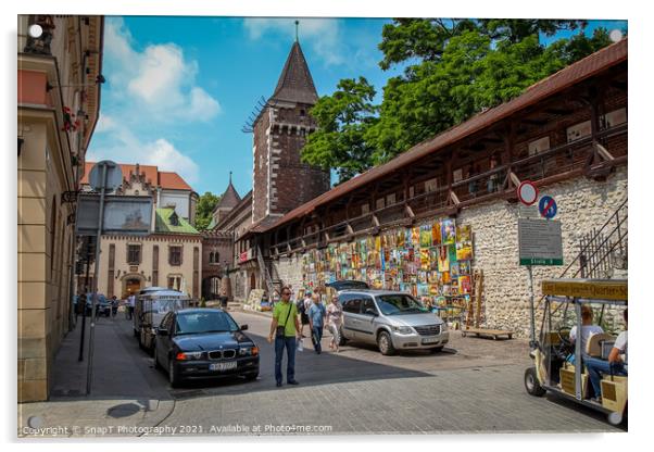 Artists pictures displayed on the wall of St. Florian's Gate on Pijarska Street, old town of Krakow, Poland Acrylic by SnapT Photography