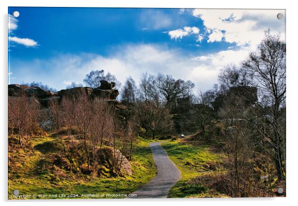 Scenic pathway through a lush park with rocky outcrops and vibrant blue sky with fluffy clouds at Brimham Rocks, in North Yorkshire Acrylic by Man And Life