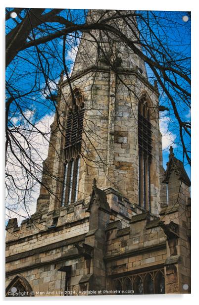 Gothic church tower with intricate stone details, framed by bare tree branches against a blue sky with fluffy clouds in York, North Yorkshire, England. Acrylic by Man And Life