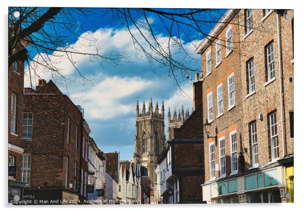 Historic European city street with traditional brick buildings and a prominent Gothic cathedral in the background under a blue sky with clouds in York, North Yorkshire, England. Acrylic by Man And Life
