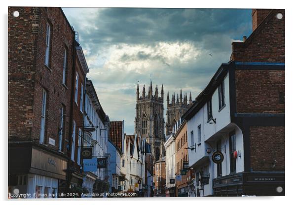 Quaint European street leading to a majestic Gothic cathedral under a dramatic sky at dusk, showcasing historical architecture and urban charm in York, North Yorkshire, England. Acrylic by Man And Life