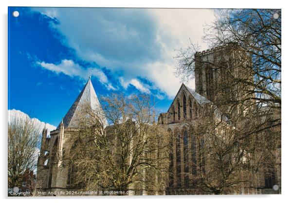 Historic medieval cathedral with Gothic architecture, featuring pointed arches and robust stone walls, set against a vibrant blue sky with fluffy clouds in York, North Yorkshire, England. Acrylic by Man And Life