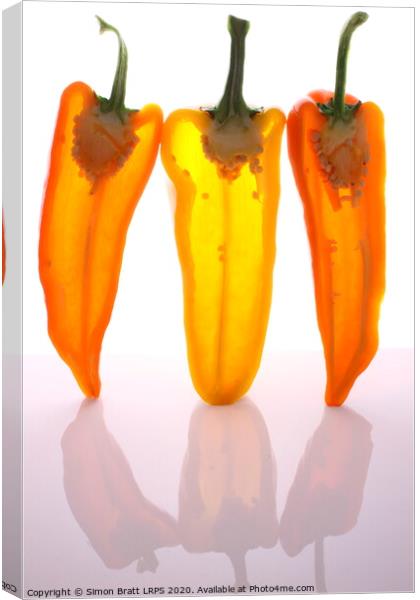 Peppers in half with light through them Canvas Print by Simon Bratt LRPS