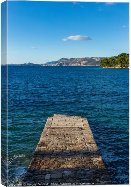 Stone pier in the sea with mountains in the background Canvas Print by Sergey Fedoskin