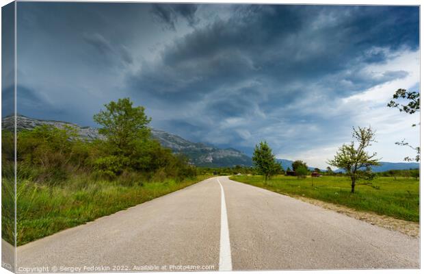 Empty countryside road in valley. Landscape with dramatic sky. A storm is coming from the mountains. Canvas Print by Sergey Fedoskin