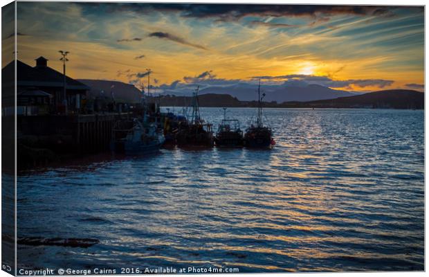 The sun sets on Oban harbour and fishing boats Canvas Print by George Cairns