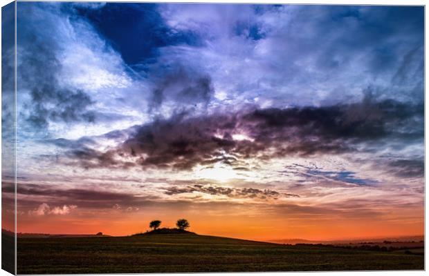 Colourful cloudy sky sunset behind a small hill Canvas Print by André Jorge
